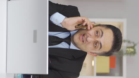 Vertical-video-of-Home-office-worker-man-talking-on-the-phone-happily.